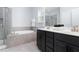Bright bathroom with a soaking tub, glass shower, double vanity with dark cabinets, and neutral tile at 3413 S Beaver Ln, Raleigh, NC 27604