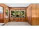 Room with wood paneling and three windows overlooking a lush green yard at 3899 Warrenton Rd, Henderson, NC 27537