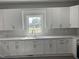 Bright kitchen featuring white cabinets, marble countertops, and a stainless steel sink beneath a window at 409 S Flanner St St, Burlington, NC 27215