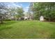 Large grassy backyard with mature trees, home, shed, and privacy fence at 515 Poplar Dr, Raleigh, NC 27603