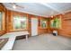 Cozy sunroom featuring wood paneled walls, neutral carpet, and abundant natural light at 515 Poplar Dr, Raleigh, NC 27603