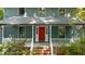 Inviting home featuring a bright red front door, covered porch, white railings and lush greenery at 522 Lochness Ln, Cary, NC 27511