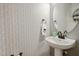 Stylish half-bathroom featuring decorative wallpaper, pedestal sink, and elegant fixtures at 524 Woodson Dr, Clayton, NC 27527