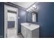 Bathroom with blue patterned wallpaper, white vanity, and a glimpse of the shower area at 5652 Laurel Crest Dr, Durham, NC 27712