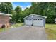 Detached two-car garage with white doors and light blue siding, nestled in a serene, wooded setting at 5652 Laurel Crest Dr, Durham, NC 27712