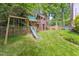 A play area with a swing, a slide, and a climbing structure in a green backyard at 7804 Tylerton Dr, Raleigh, NC 27613