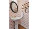 Stylish powder room featuring decorative wallpaper, pedestal sink, and a round mirror at 7804 Tylerton Dr, Raleigh, NC 27613