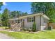 Close-up of a brick home with a covered front porch, well-manicured landscaping, and a gravel driveway at 827 Loop Rd Rd, Burlington, NC 27217