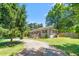 View of a charming brick home featuring manicured bushes, a wooden fence, and gravel driveway at 827 Loop Rd Rd, Burlington, NC 27217