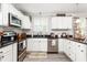 Bright kitchen featuring stainless steel appliances, white cabinets, black countertops and light-colored flooring at 827 Loop Rd Rd, Burlington, NC 27217