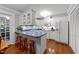 Bright kitchen with white cabinets, blue countertops, hardwood floors, and bar seating at the island at 8513 Applecross Cir, Apex, NC 27539