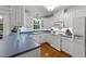 Well-lit kitchen featuring white cabinets, blue countertops, hardwood floors, and modern appliances at 8513 Applecross Cir, Apex, NC 27539