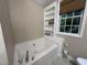 Bright bathroom featuring a soaking tub with built-in shelves and a window view at 1312 High Ridge Dr, Mebane, NC 27302