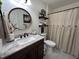 A stylish bathroom with a dark wood vanity, a round mirror, and a shower featuring a buttoned curtain at 1312 High Ridge Dr, Mebane, NC 27302