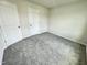 A bright bedroom featuring neutral walls, soft gray carpet, and minimalist white door and trim at 138 Sourgum Ct, Zebulon, NC 27597