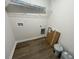 A functional laundry area with overhead shelving, wood-look flooring, and utility connections at 138 Sourgum Ct, Zebulon, NC 27597