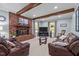 Inviting living room featuring a brick fireplace, beamed ceiling, and plush leather seating at 148 Shadowbrook Dr, Henderson, NC 27537