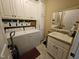 Well-lit laundry room with white appliances, storage cabinets, and a utility sink at 1655 Kingfisher Ct, Nashville, NC 27856