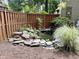 Fenced-in backyard featuring a small pond surrounded by rocks, leafy plants, and tall grasses at 1707 Falls Church Rd, Raleigh, NC 27609