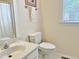 Clean half bath with tile flooring features a toilet, sink with vanity, and blind-covered window at 1707 Falls Church Rd, Raleigh, NC 27609