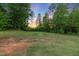 A lush green backyard surrounded by mature trees, perfect for outdoor activities at 175 Lockamy Ln, Youngsville, NC 27596