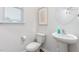 Simple half-bath with a white toilet, pedestal sink, round mirror, artwork, and natural light from a window at 1909 Hinesley Dr, Durham, NC 27703