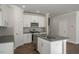 White kitchen with stainless steel appliances, island sink, and bright lighting for a modern cooking space at 1915 Hinesley Dr, Durham, NC 27703