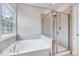 Bright bathroom featuring a large window, separate shower, and soaking tub at 200 Chateau Way, Angier, NC 27501