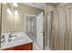 Modern bathroom featuring double sinks, a vanity with cherry wood cabinets, a large mirror, and a shower-tub combo at 208 Beckingham Loop, Cary, NC 27519