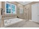 This primary bathroom features a large soaking tub, seamless glass shower, and an elegant window at 216 Colonial Ridge Dr, Pittsboro, NC 27312