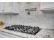 Close-up of gas cooktop with granite counters and white marble backsplash at 216 Colonial Ridge Dr, Pittsboro, NC 27312