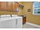 Bright laundry room featuring a white washer and dryer, wooden cabinets, and stylish decor at 216 Colonial Ridge Dr, Pittsboro, NC 27312