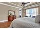 Relaxing main bedroom offers tray ceiling, wood floors, and a large dresser with a decorative mirror at 216 Colonial Ridge Dr, Pittsboro, NC 27312