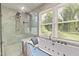 Bright bathroom featuring a dual shower head and a modern bathtub with jets and a glass partition at 2315 Oxford Rd, Henderson, NC 27536
