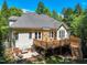 A large, pale yellow home with a stone chimney and wood deck is surrounded by green grass and mature trees at 2709 Penfold Ln, Wake Forest, NC 27587