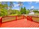 Backyard with a vibrant red wood deck, surrounded by lush greenery and a well-maintained lawn at 32 Lattimore Rd, Cameron, NC 28326