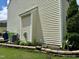 Side view of the home exterior and garden bed with green shrubs, other plants, and rock retaining wall at 3848 Griffis Glen Dr, Raleigh, NC 27610