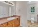 Bathroom with vanity and mirror, toilet next to a window, and laminate flooring at 397 Meadow Rd, Kenly, NC 27542
