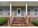 Welcoming front porch with brick stairs, wood railings, and classic exterior lighting at 397 Meadow Rd, Kenly, NC 27542