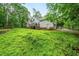 View of the house and deck from the expansive, grassy backyard and surrounded by trees at 50 Peggy Ct, Raleigh, NC 27603