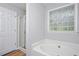 Bathroom featuring a soaking tub, glass block window, and separate shower at 50 Peggy Ct, Raleigh, NC 27603
