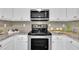 Close up of a modern kitchen with stainless steel appliances, granite counters, tiled backsplash, and white cabinets at 522 Crossview Ln, Durham, NC 27703