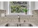 Close up of a modern kitchen sink with stainless steel appliances, granite counters, tiled backsplash, and white cabinets at 522 Crossview Ln, Durham, NC 27703