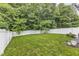 Backyard with green grass, a white fence, and mature trees at 5412 Robbins Dr, Raleigh, NC 27610