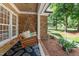 Inviting covered front porch features a porch swing, brick accents, and patterned rug for outdoor relaxation at 5916 Two Pines Trl, Wake Forest, NC 27587