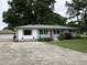 Charming single-story home featuring a red front door, well-maintained lawn, and a detached garage at 704 S Mineral Springs Rd, Durham, NC 27703