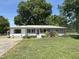 Single-story home featuring a red front door, lush lawn, and beautiful shade trees at 704 S Mineral Springs Rd, Durham, NC 27703
