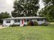Charming single story home with well-manicured front yard and inviting red front door at 704 S Mineral Springs Rd, Durham, NC 27703