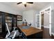 A well-lit home office features dark wood built-ins, a ceiling fan, and a sophisticated, textured desk at 713 Liberty Cliff Dr, Cary, NC 27519