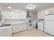 Well-lit kitchen featuring white cabinets, marble countertops, and modern appliances, including washer and dryer at 725-727 Locust Ln, Raleigh, NC 27603